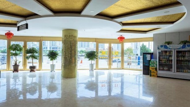 Un hall d’entrée spacieux, doté d’un haut plafond, de grandes fenêtres et d’un pilier central.