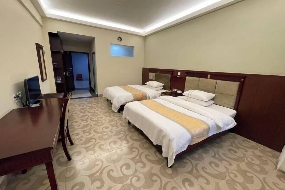 Habitació d'hotel amb dos llits, una taula de treball i una televisió.