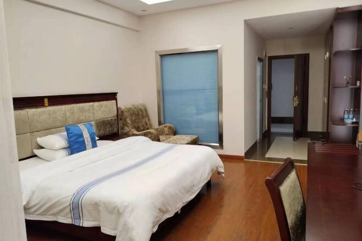 Una habitació d'hotel amb un llit, una cadira, un escriptori i un armari.
