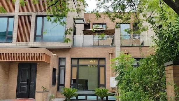 Un edificio moderno con fachada de ladrillo, ventanas grandes y un pequeño espacio al aire libre con plantas.