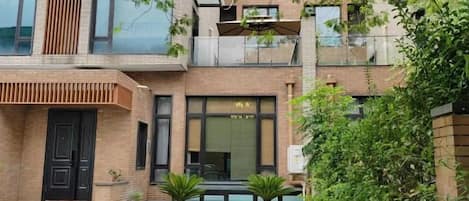 A modern two-story building with a flat roof, large windows, and a balcony.
