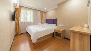 Una habitación de hotel con cama, mesita de noche y un escritorio pequeño con silla.