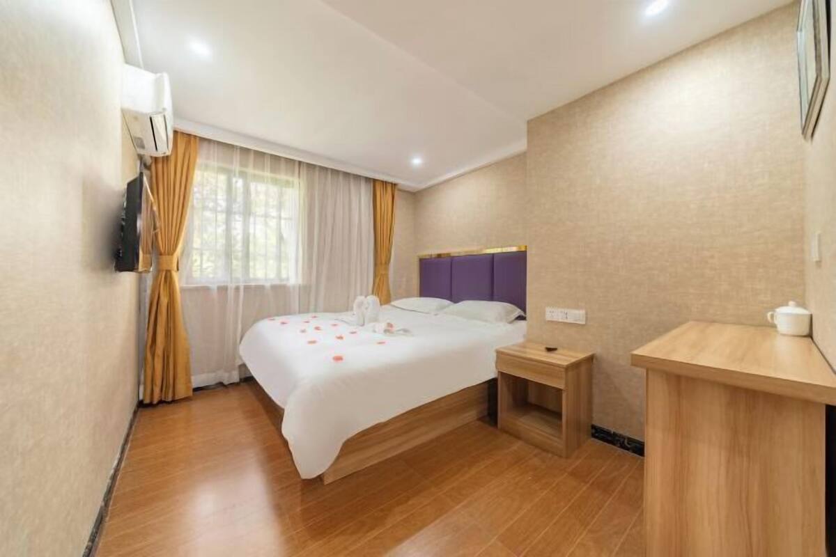 A hotel room with a bed, bedside table, and a small desk with a chair.