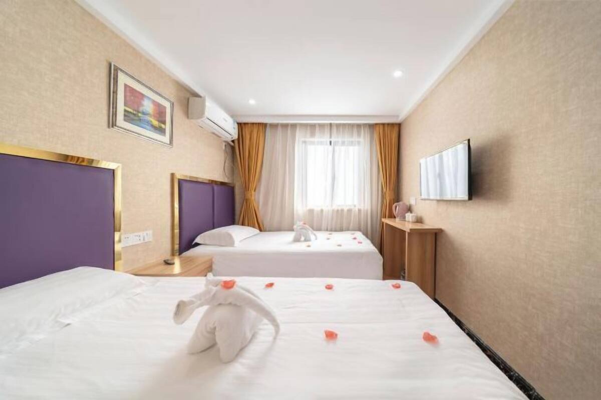 A hotel room with two beds, a TV, and a painting on the wall.