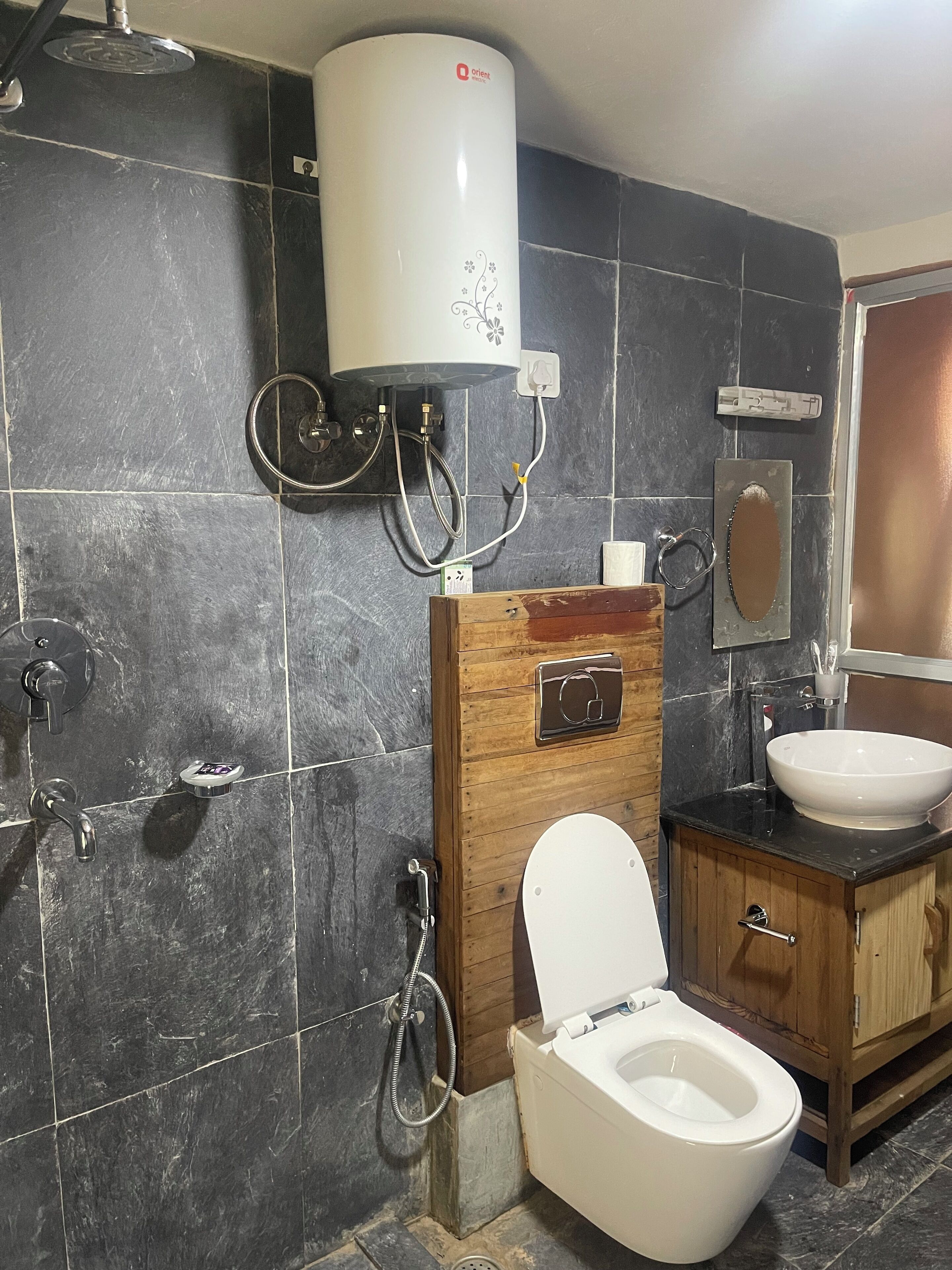 Un baño con inodoro, lavamanos, ducha y calentador de agua.