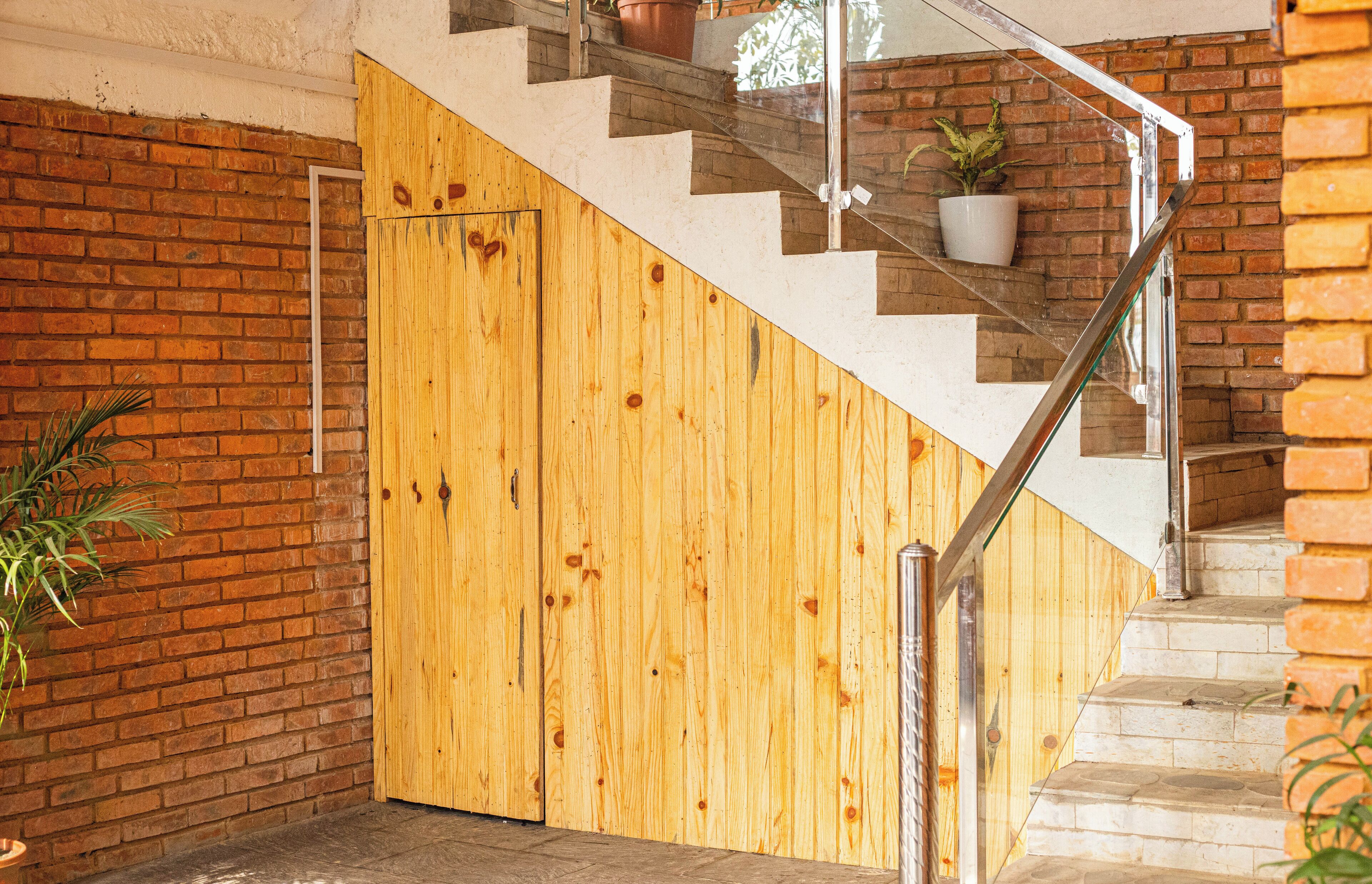 A staircase with a wooden wall and a glass railing.