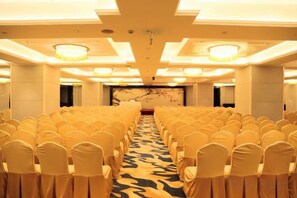 A conference room with rows of chairs, a patterned carpet, and a large screen at the front. - KinDream Hotel (Yongkang)