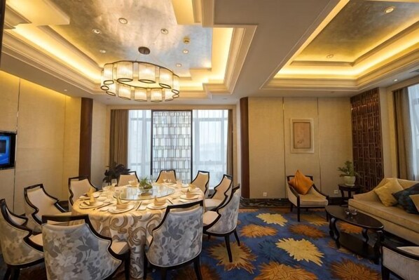 A dining area with a round table, chairs, and a chandelier.