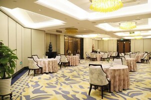 Un salón de conferencias con mesas redondas, sillas y una lámpara de araña grande.
