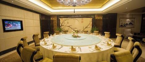A conference room with a round table, chairs, and a chandelier.