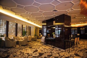 A hotel lobby with a patterned carpet, seating area, and a reception desk.