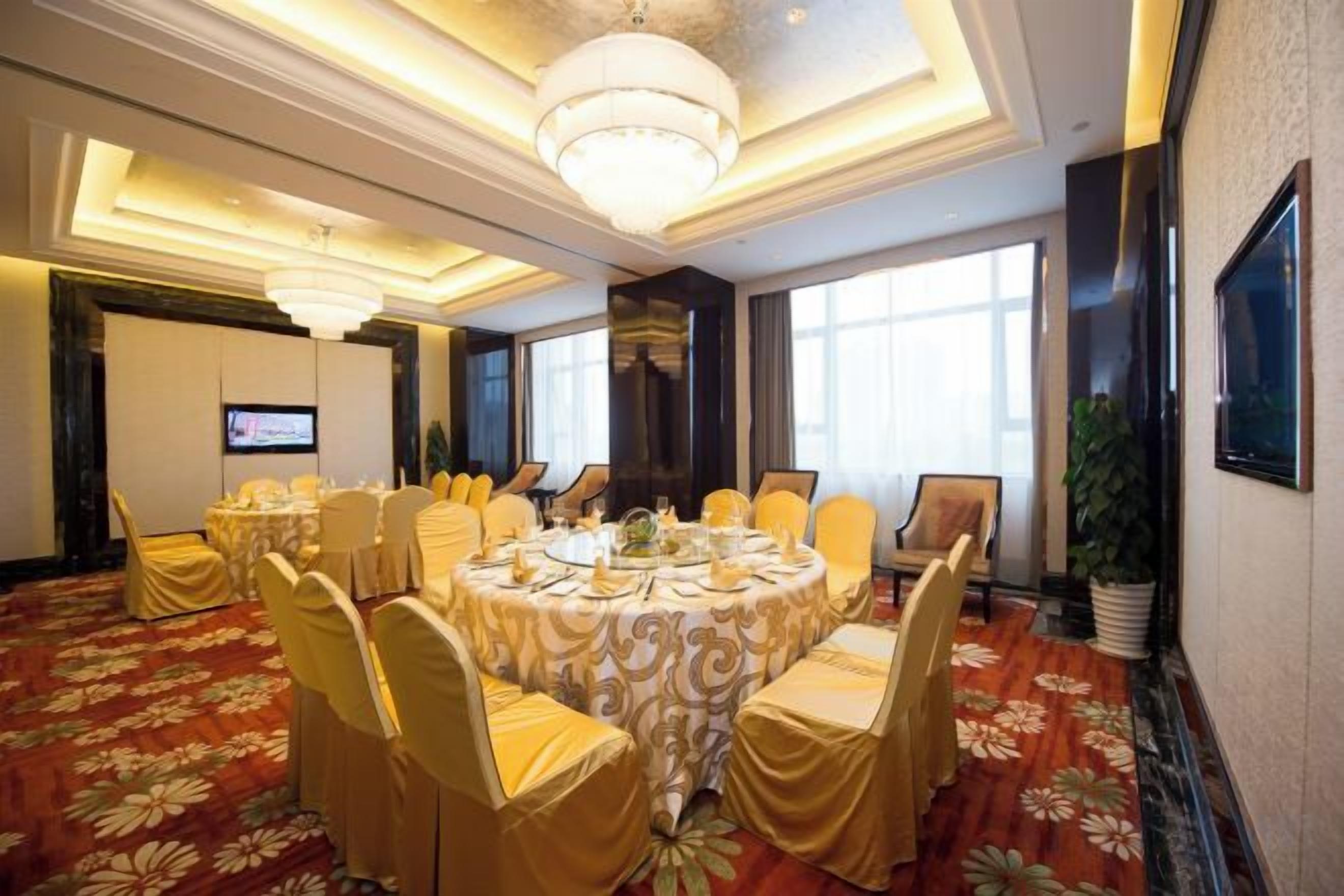 A conference room with round tables, chairs, and a large chandelier.