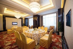 A conference room with round tables, chairs, and a large chandelier.
