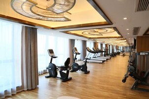 Un gimnasio con equipo de ejercicio, ventanas amplias y suelo de madera.