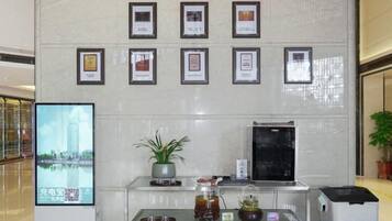 A reception area with framed awards on the wall, a digital screen, and a plant on a glass table.