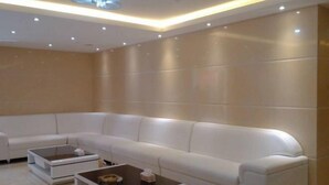 Uma sala de estar moderna com um sofá modular branco, duas mesinhas laterais e iluminação embutida no teto.
