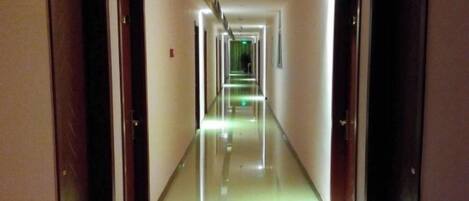 A long, narrow hotel corridor with doors on both sides and a reflective floor.