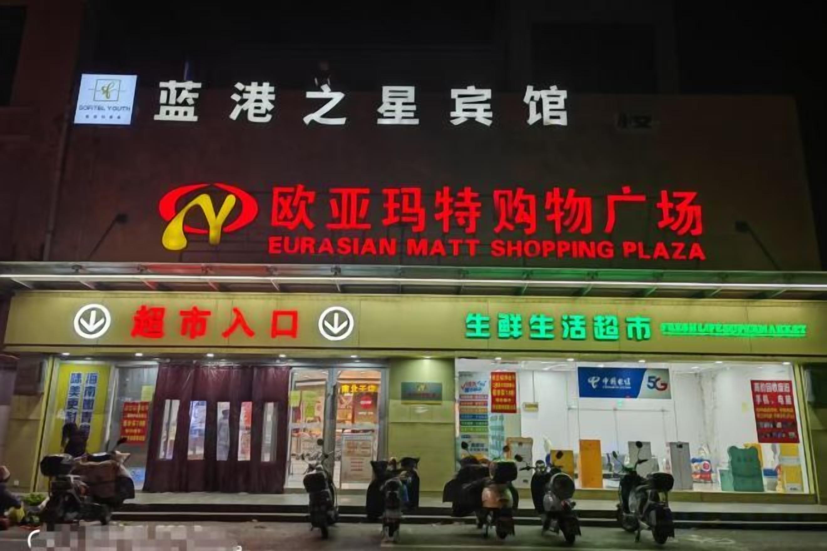 Un centro comercial con un letrero llamativo que indica Eurasian Matt Shopping Plaza.