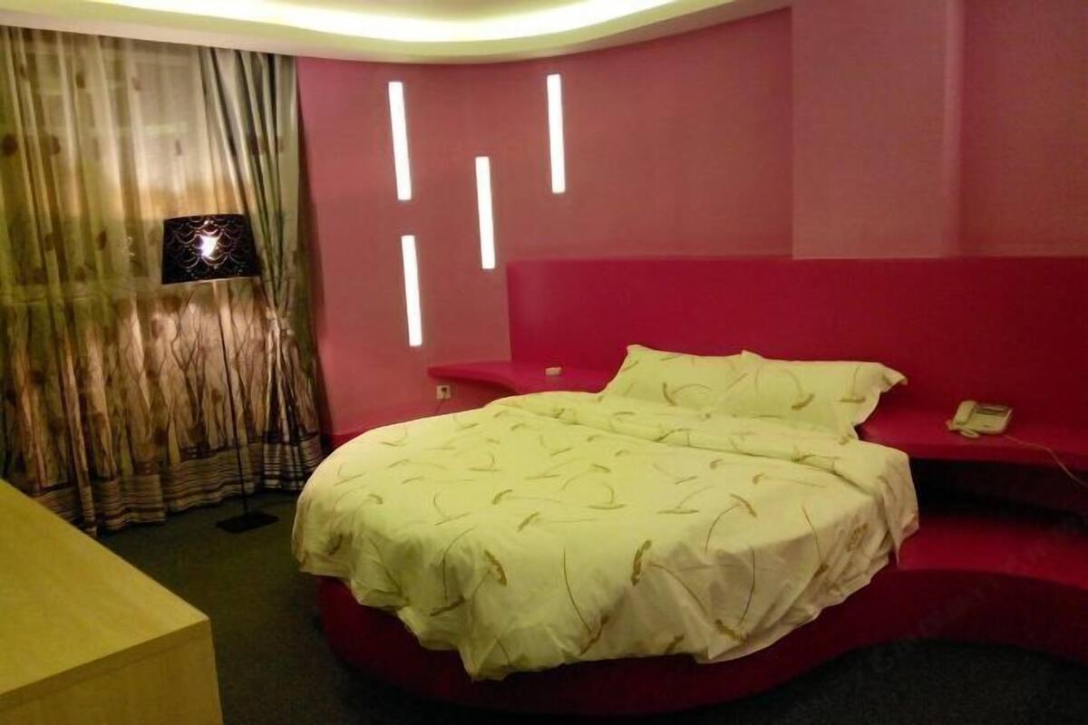A bedroom with a bed, a desk, and a curtain.