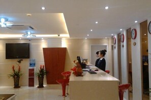 A hotel reception area with a reception desk, a TV mounted on the wall, and a modern interior design. - Langang Zhixing Hostel (Shanghai)