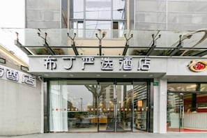 The exterior of a hotel with a modern facade, large glass doors, and a visible restaurant or dining area inside. - Pod Inn Yanxuan Hotel (Shanghai Long-Distance Bus Terminal) (Shanghai)