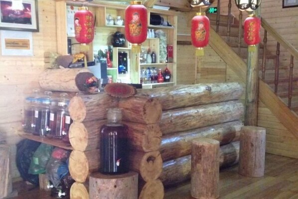 A wooden interior with a log bench, shelves with bottles, and red lanterns. - Senlinyu Villa (Fenglin County)