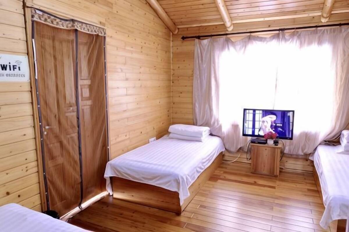 Una habitación de madera con dos camas, un televisor y un armario.