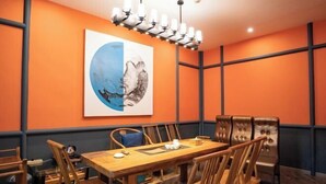 A dining area with a wooden table and chairs, a chandelier, and a large wall painting. - Federal Hotel (Meizhou)