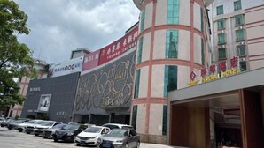 A hotel with a curved facade, multiple floors, and a parking lot with several cars. - Federal Hotel (Meizhou)