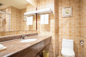 A bathroom with a marble sink, a mirror, a towel rack, a toilet, and a shower.