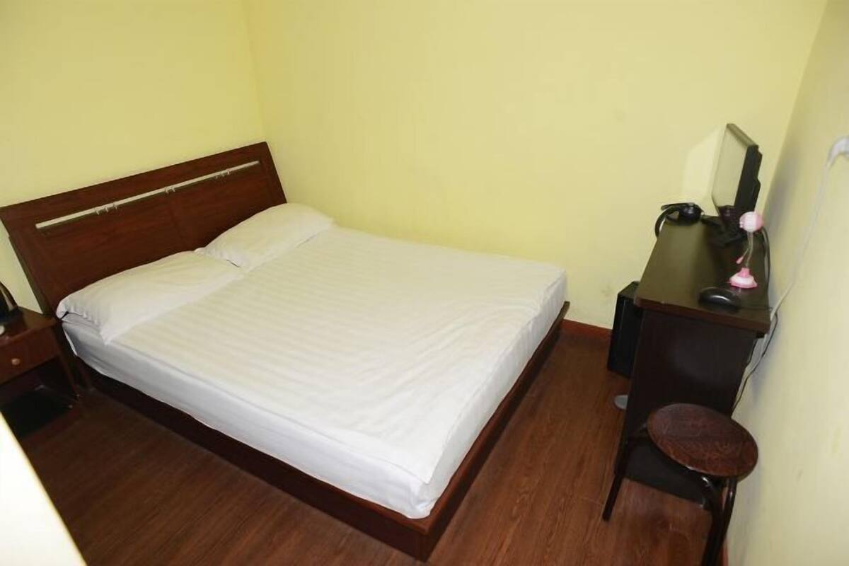 A single bed with a wooden headboard in a room with yellow walls and wooden flooring.