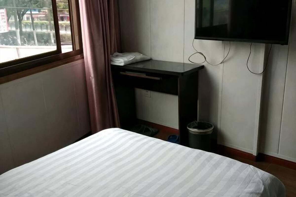 A hotel room with a bed, a desk, a TV, and a window with curtains.