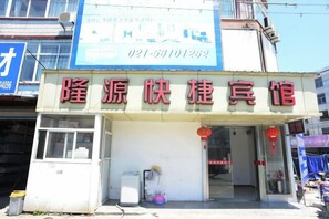 A building with a sign in Chinese characters, a visible entrance, and a small window on the ground floor. - Longyuan Express Hotel (Shanghai)