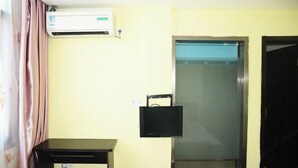 A room with a bed, an air conditioner, a small table, a window, and a door. - Longyuan Express Hotel (Shanghai)