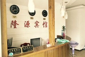 A reception desk with clocks, a wooden counter, and a sign with Chinese characters. - Longyuan Express Hotel (Shanghai)
