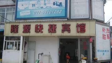 A building with a sign that reads '隆源快捷宾馆' and a contact number '021-58101262'.