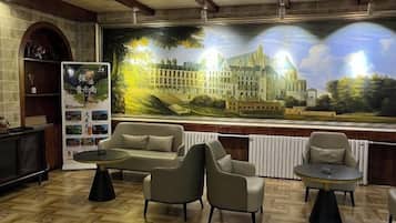 A lobby with a large mural, seating area, and a fireplace.
