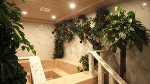Eine Marmortreppe mit Holzhandläufen und einer Wand, die mit Grünpflanzen und roten Blüten verziert ist.