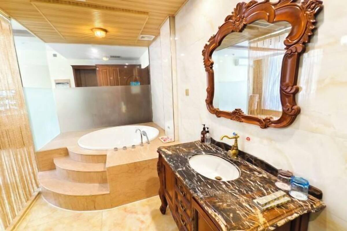 A bathroom with a marble sink, wooden vanity, and a large mirror.