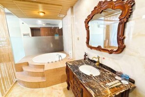 Un baño con lavamanos de mármol, tocador de madera y un espejo grande.