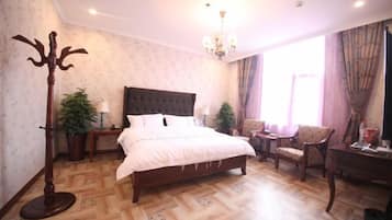 A hotel room with a large bed, a sitting area with a chair, a small table, and a floor lamp.