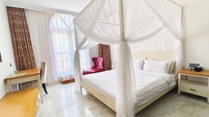 Ein Schlafzimmer mit Himmelbett, Schreibtisch, Stuhl und Nachttisch.