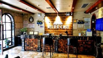 A bar area with wooden flooring, a counter with stools, and a large window on the left.