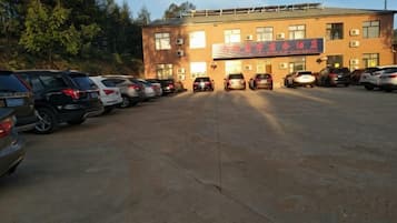 A parking lot with several cars parked in front of a building with multiple windows and a sign.