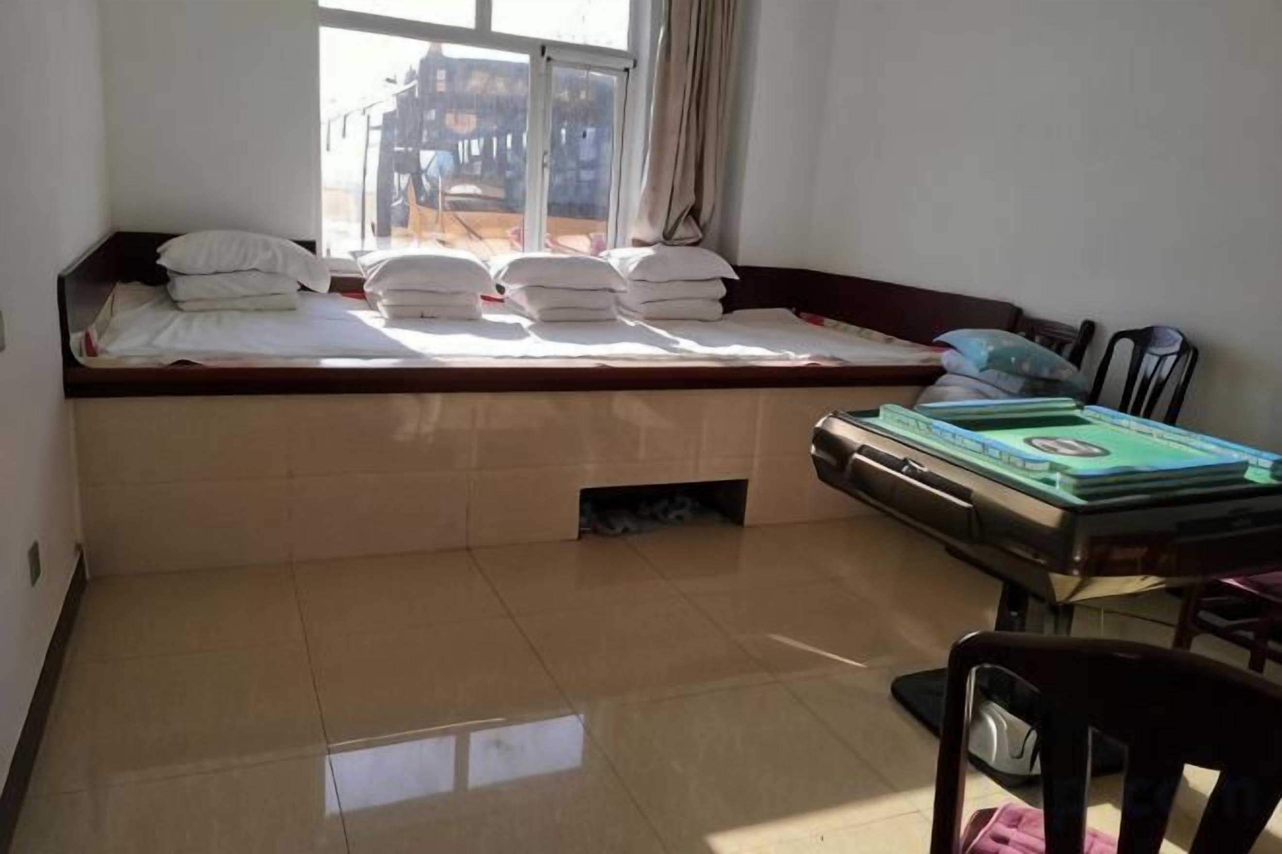 A room with a bed, a table with books, and a window.