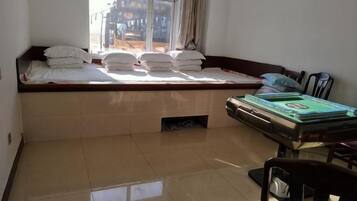 A room with a bed, a table with books, and a window.