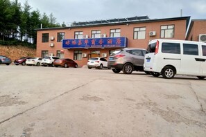 A building with a sign indicating it is a hotel. There are several cars parked in front. - Bingyugou Jiahua Business Hotel (Zhuanghe)