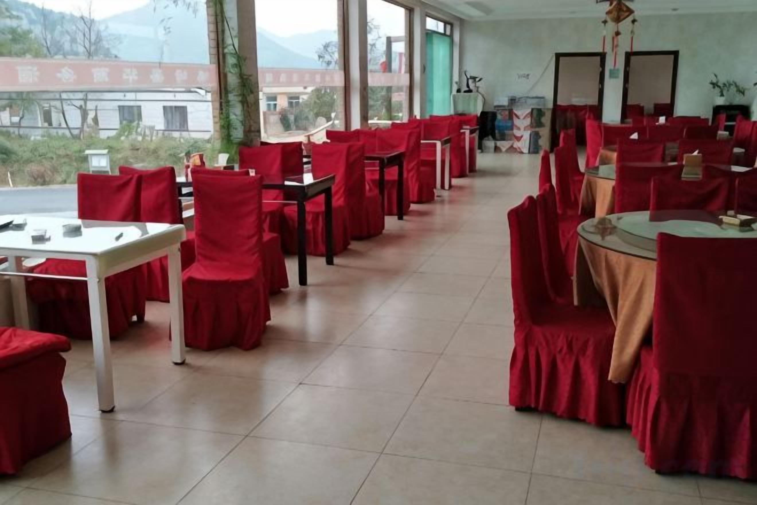 Un espace repas avec des tables et des chaises, de grandes fenêtres et une vue sur l’extérieur.