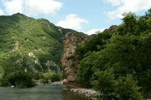 Et naturligt landskab med en flod, en klippe og frodig vegetation.