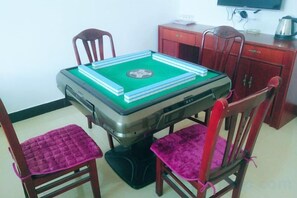 Una mesa de comedor con superficie de fieltro verde, rodeada de sillas de madera con asientos acolchados.